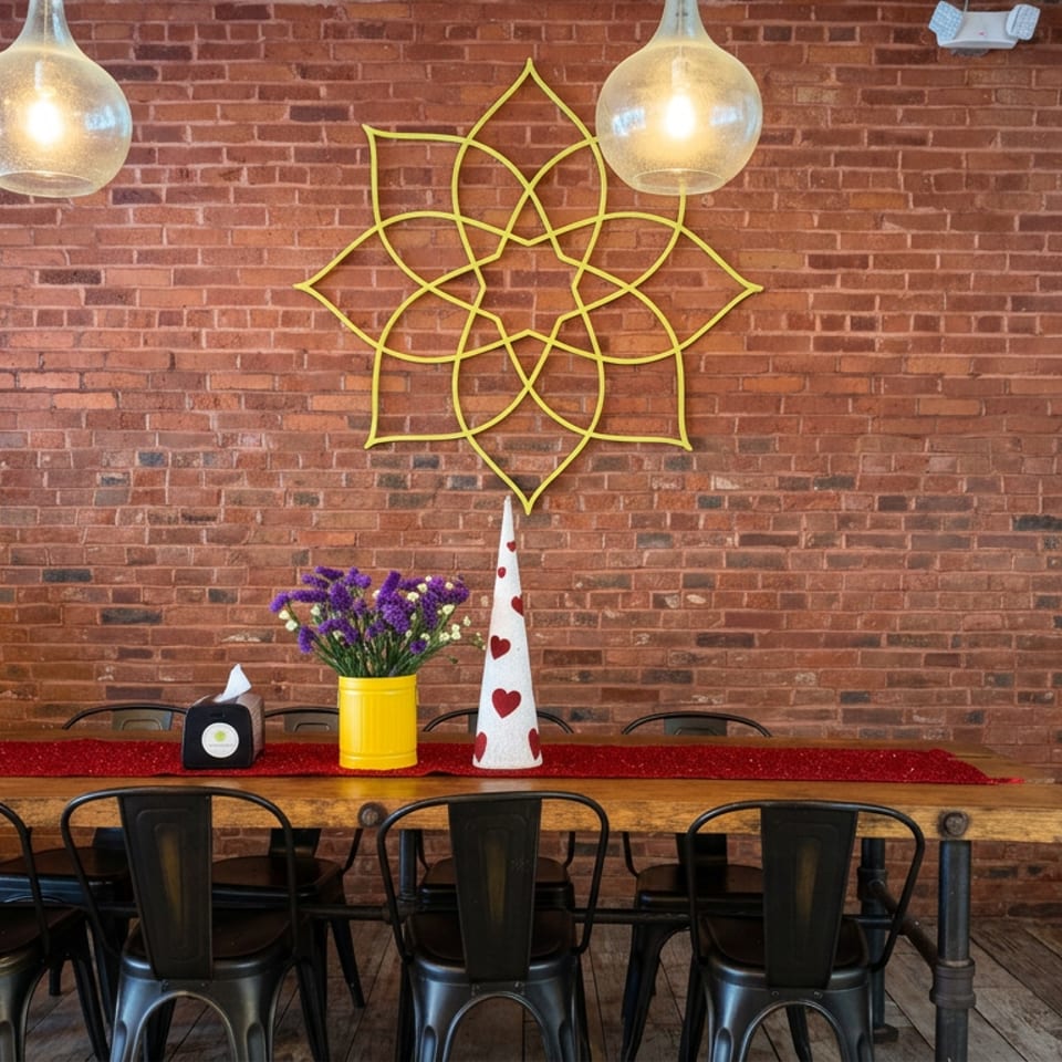 Rustic restaurant dining area with a long wooden table, black metal chairs, brick wall, pendant lights, and festive decorations.